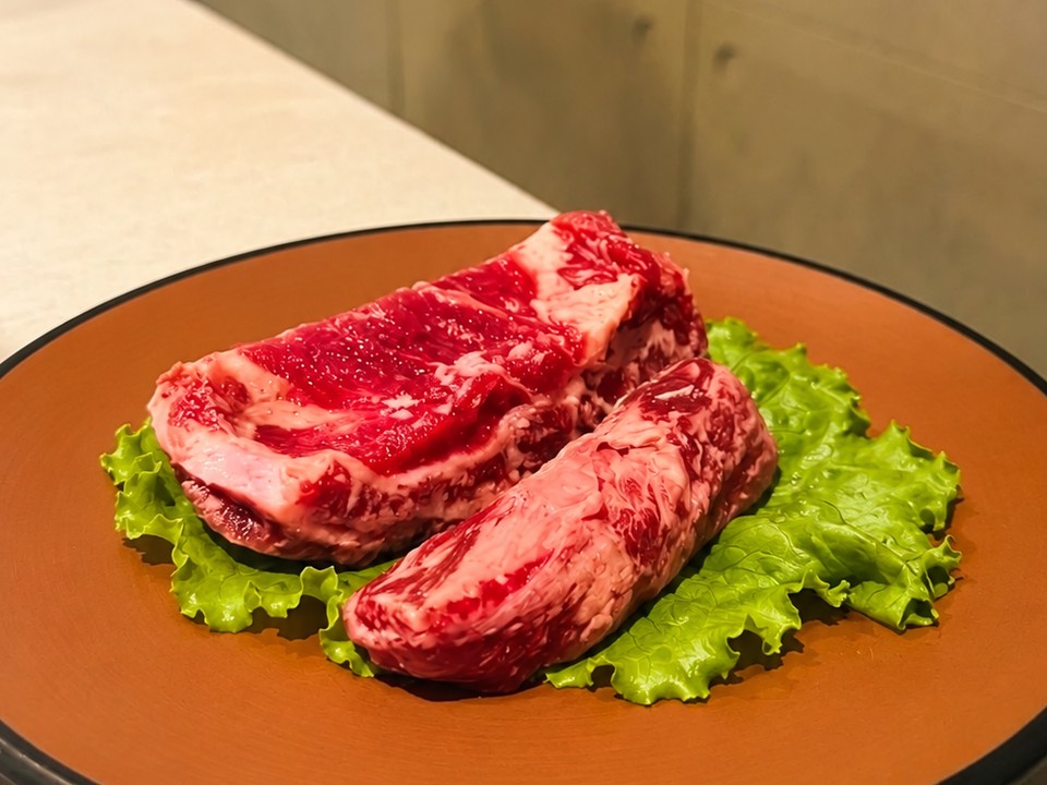 料韓男的兩塊生牛肋條，墊著生菜放在陶盤上
